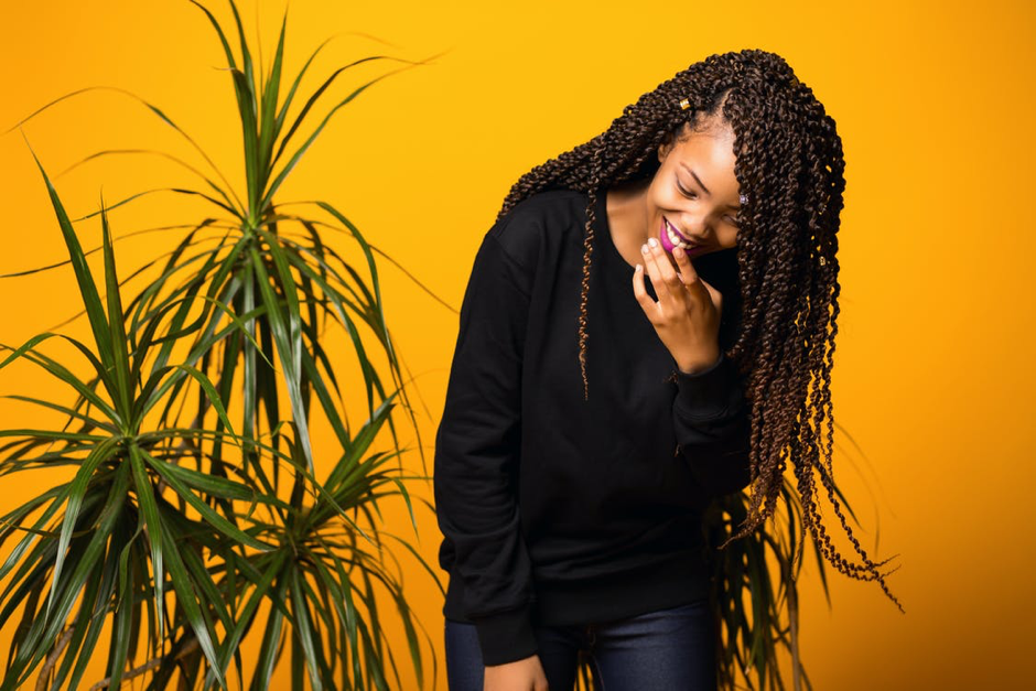 Optimistic young black female having fun in yellow studio